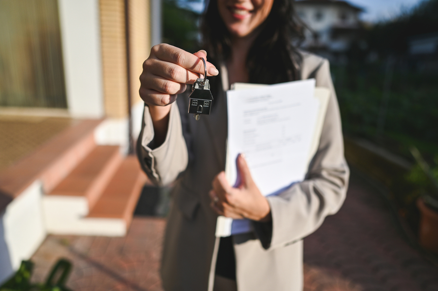 A real estate agent holding some documents and the keys to a new home.
